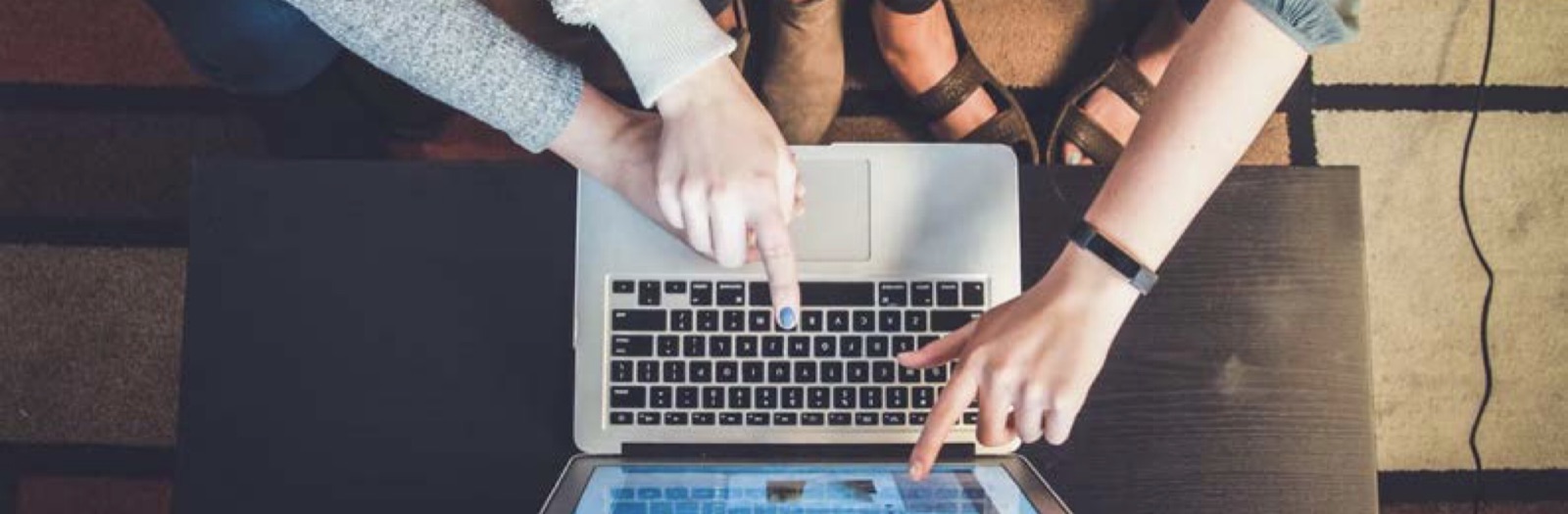 Two people pointing at a laptop screen together