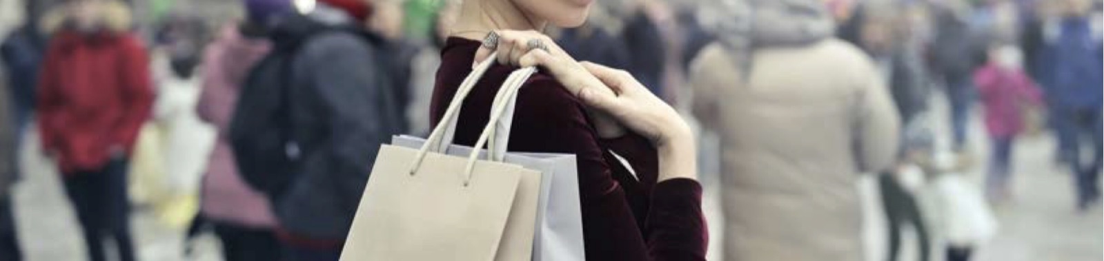 A shopper carrying shopping bags through a busy crowd