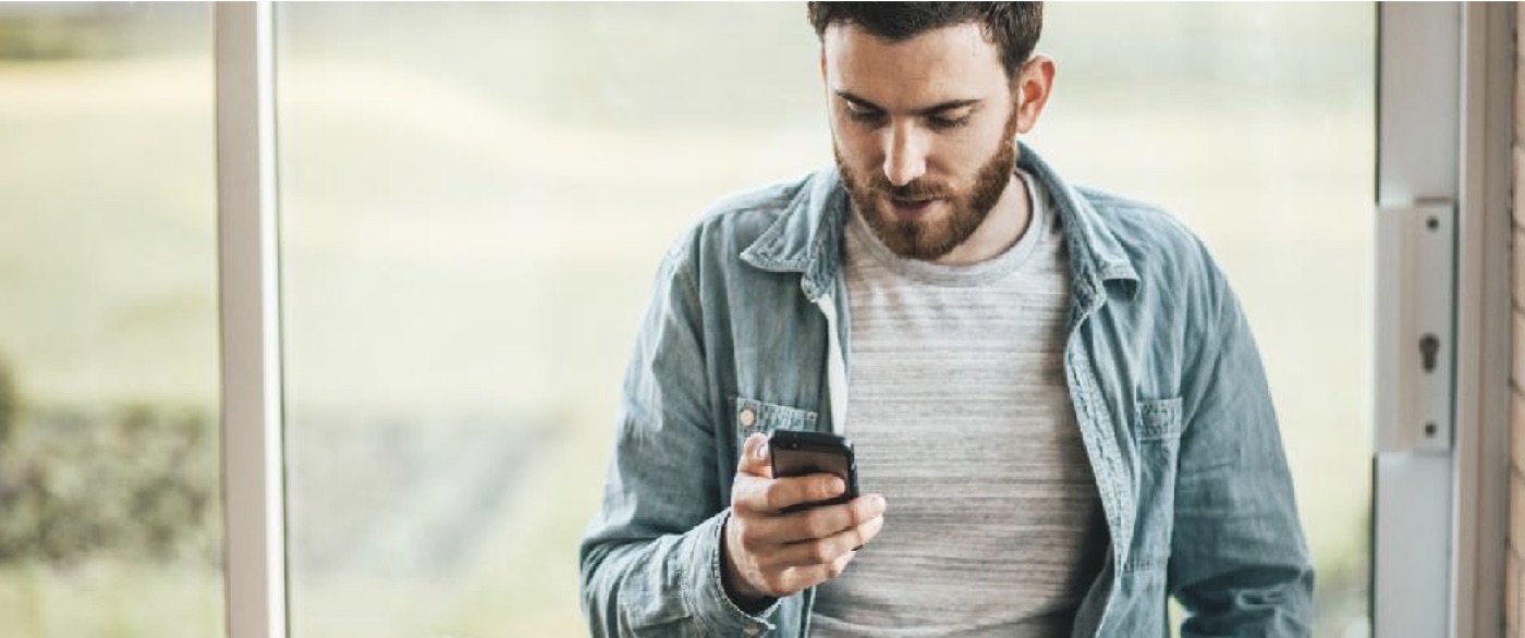 A man looking down at the smartphone in his hand