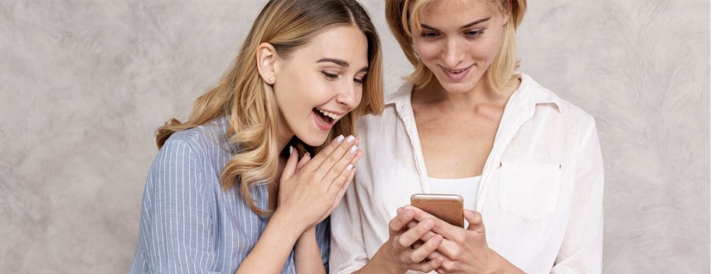 Two women smiling as they look together at a phone
