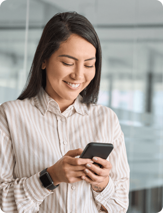 A woman smiling at her phone in an office